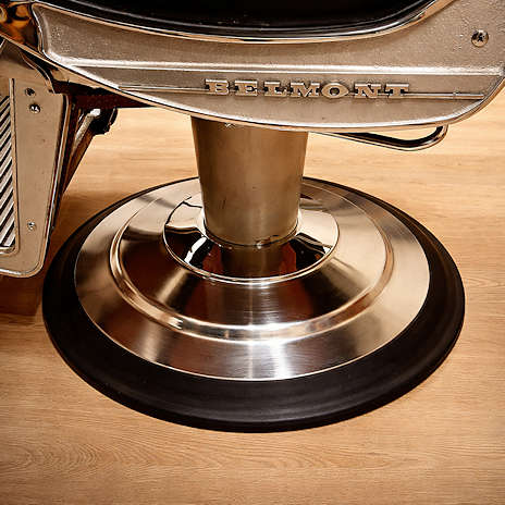 Detailopname van de poot van een klassieke kappersstoel met chroommetaal en getextureerde vloer in retro interieur